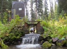 FFS Program Manager Colin Hardy removes debris from the Pack Creek flume at the Tenderfoot Creek Experimental Forest, Helena-Lewis and Clark National Forest, Montana. 2015